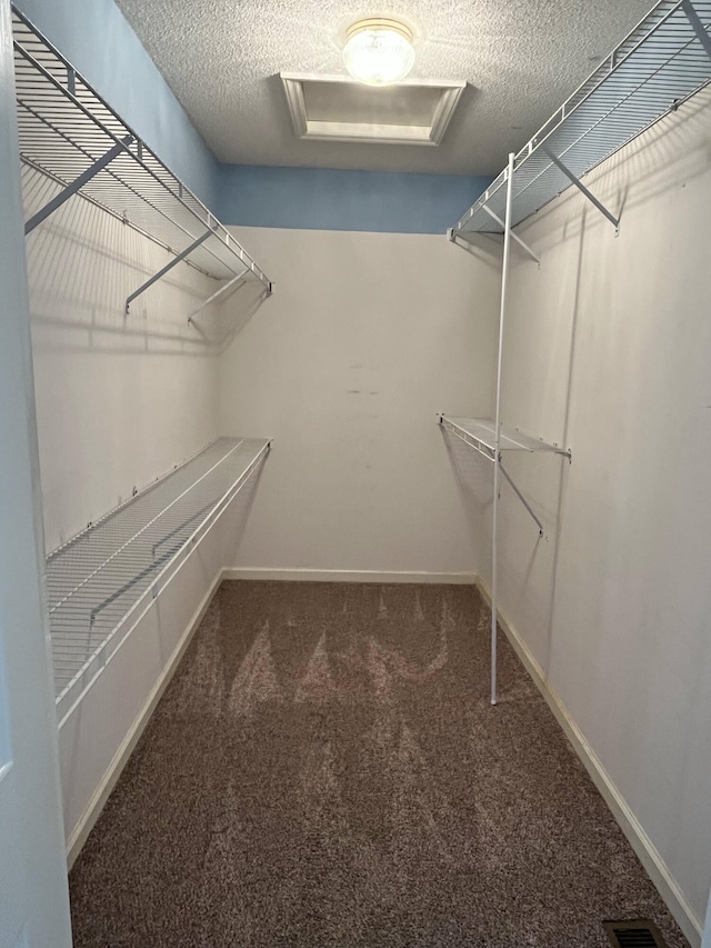 spacious closet with attic access, visible vents, and carpet floors