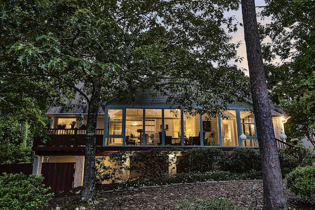 back of house at dusk featuring a sunroom