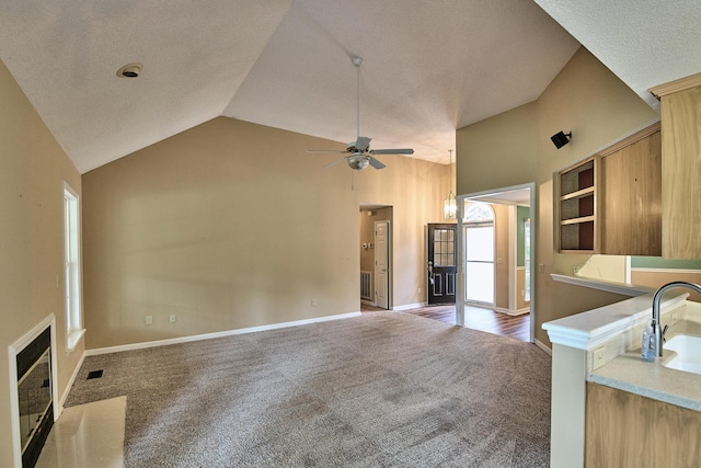 unfurnished living room with ceiling fan, a sink, visible vents, baseboards, and carpet