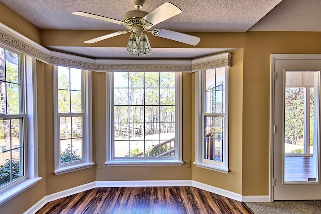 interior space featuring a textured ceiling, wood finished floors, and baseboards