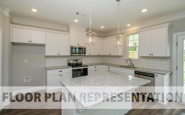 kitchen with decorative backsplash, appliances with stainless steel finishes, sink, a center island, and white cabinetry