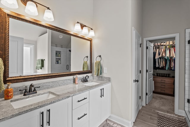 bathroom with a spacious closet, double vanity, a sink, and a shower stall