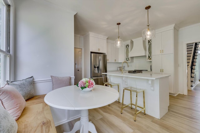 3555 Watervale Way, Martinez, GA 30907 - kitchen with stainless steel fridge, custom exhaust hood, a kitchen bar, glass insert cabinets, and light wood finished floors