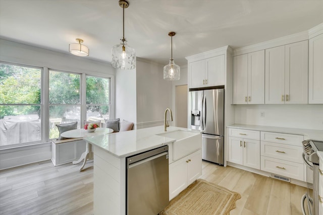 3555 Watervale Way, Martinez, GA 30907 - kitchen with appliances with stainless steel finishes, a sink, white cabinetry, light wood finished floors, and decorative light fixtures