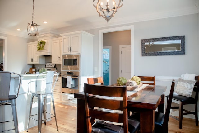 dining area featuring light hardwood / wood-style flooring, crown molding, and a chandelier