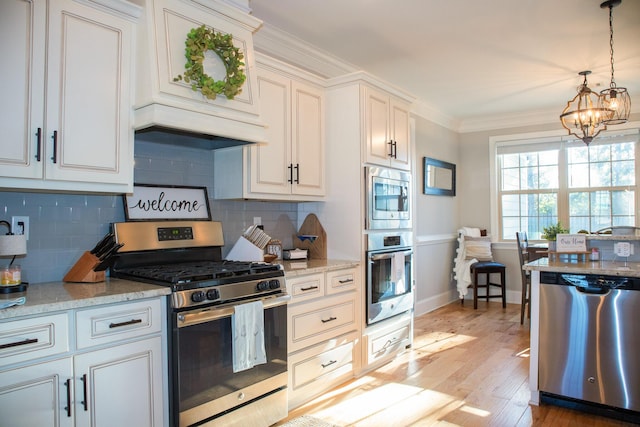 kitchen featuring decorative backsplash, crown molding, hanging light fixtures, stainless steel appliances, and a chandelier