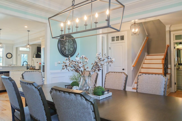 dining space featuring ornamental molding, light hardwood / wood-style flooring, and sink