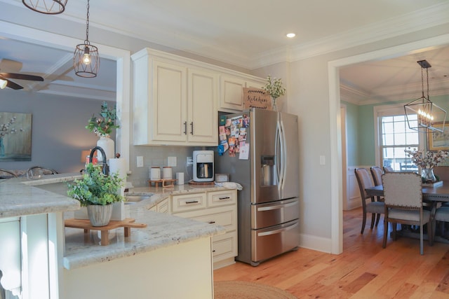 kitchen with decorative light fixtures, stainless steel fridge, and light stone counters