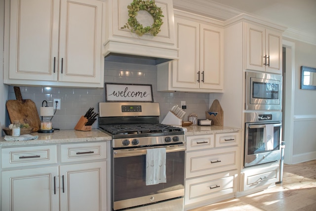 kitchen featuring light stone counters, premium range hood, appliances with stainless steel finishes, and tasteful backsplash