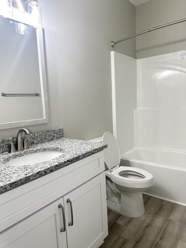 full bathroom with hardwood / wood-style floors, vanity, bathtub / shower combination, and toilet