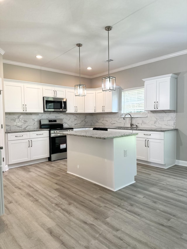 kitchen featuring light stone countertops, stainless steel appliances, sink, pendant lighting, and white cabinetry