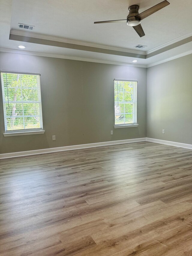 unfurnished room with light hardwood / wood-style floors, a raised ceiling, and crown molding