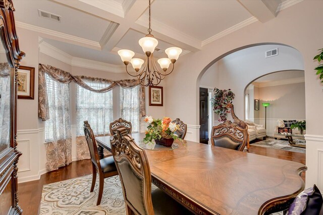 dining room featuring dark hardwood / wood-style flooring, coffered ceiling, crown molding, beam ceiling, and an inviting chandelier