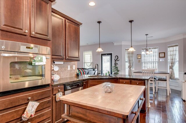 kitchen with sink, dark wood-type flooring, kitchen peninsula, decorative backsplash, and appliances with stainless steel finishes