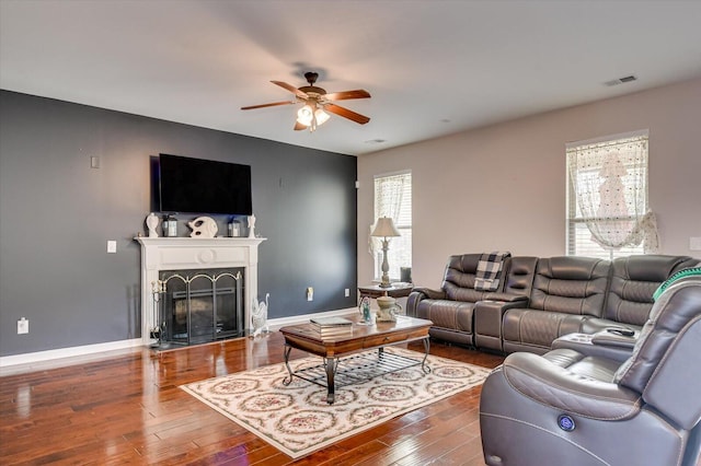 living room with dark hardwood / wood-style flooring, ceiling fan, and a premium fireplace