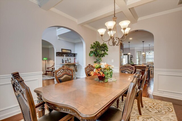 dining room featuring coffered ceiling, an inviting chandelier, beamed ceiling, hardwood / wood-style floors, and ornamental molding