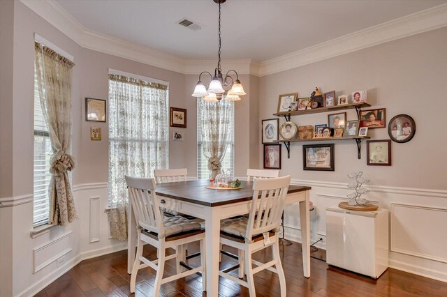 dining area featuring dark hardwood / wood-style floors, an inviting chandelier, and crown molding