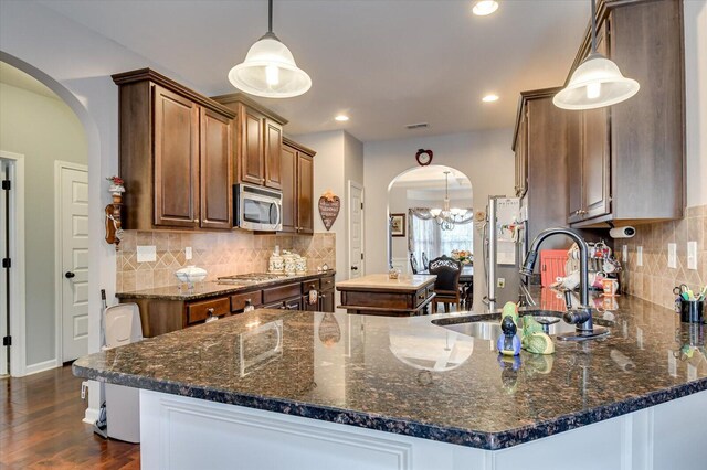 kitchen with decorative light fixtures, a chandelier, appliances with stainless steel finishes, and dark stone counters