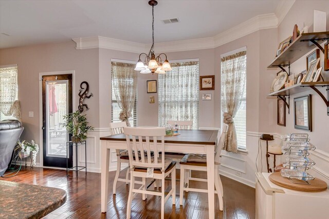 dining area with crown molding, dark wood-type flooring, and an inviting chandelier