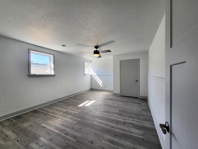 empty room with visible vents, a textured ceiling, baseboards, and wood finished floors