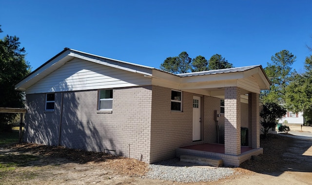 view of side of property with metal roof and brick siding