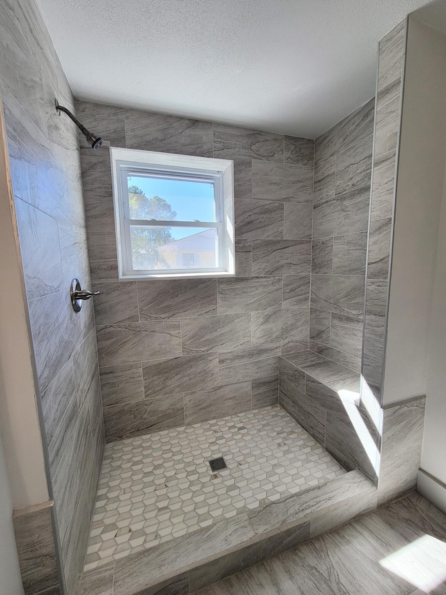 full bath featuring a textured ceiling and tiled shower