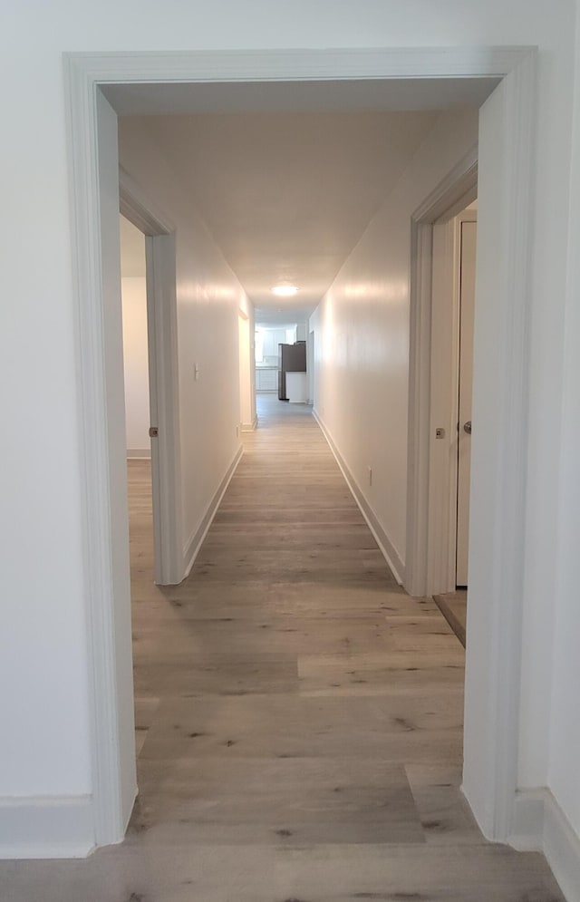 hall featuring light wood finished floors and baseboards