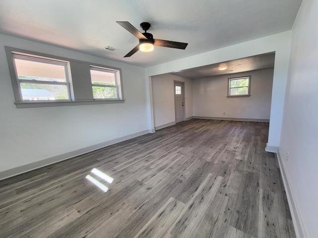 unfurnished room with a healthy amount of sunlight, baseboards, visible vents, and wood finished floors