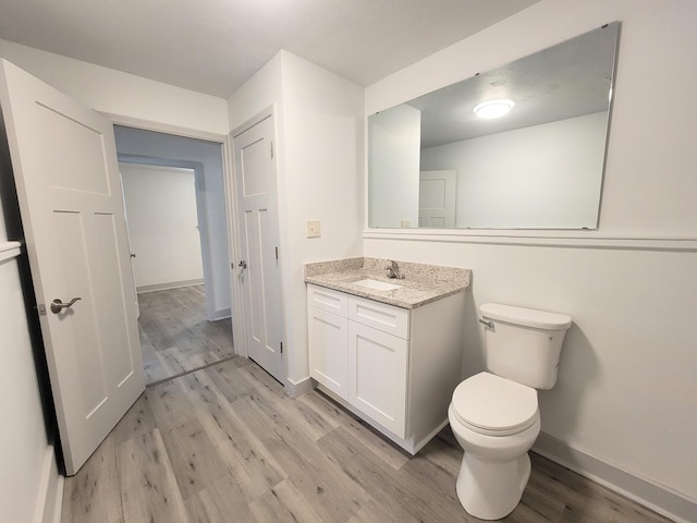 bathroom with vanity, wood finished floors, toilet, and baseboards