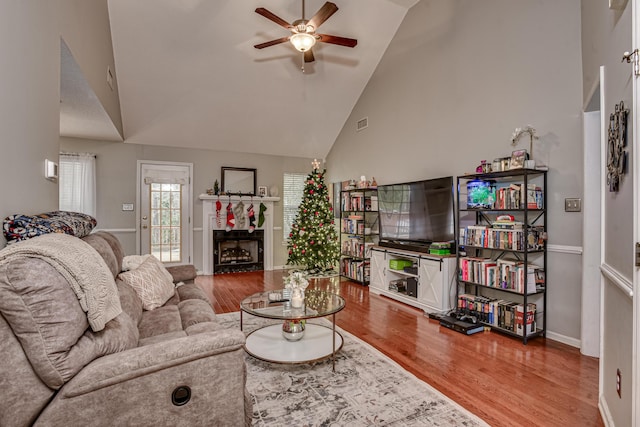 living room with hardwood / wood-style floors, ceiling fan, and high vaulted ceiling