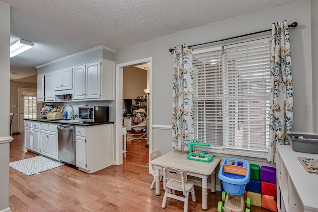 kitchen featuring white cabinetry, sink, stainless steel appliances, light hardwood / wood-style floors, and a textured ceiling