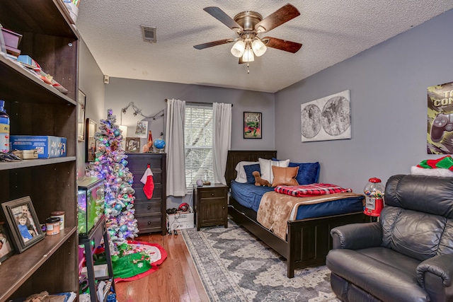 bedroom with ceiling fan, a textured ceiling, and light wood-type flooring