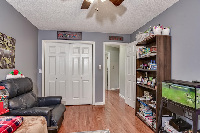 living area with ceiling fan, light hardwood / wood-style floors, and a textured ceiling