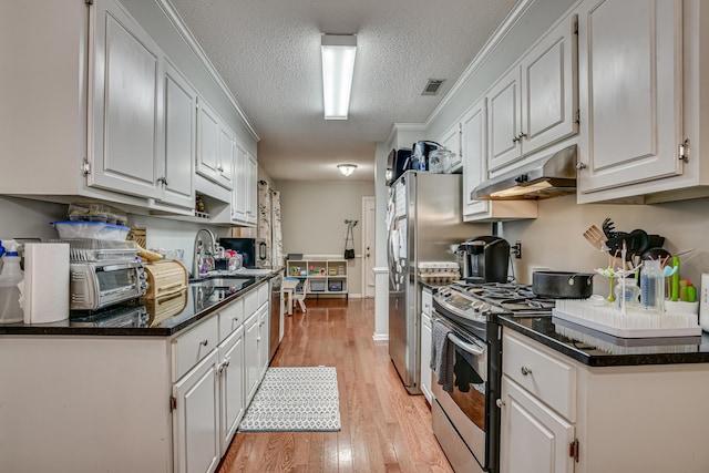 kitchen with sink, light wood-type flooring, a textured ceiling, gas stove, and white cabinetry