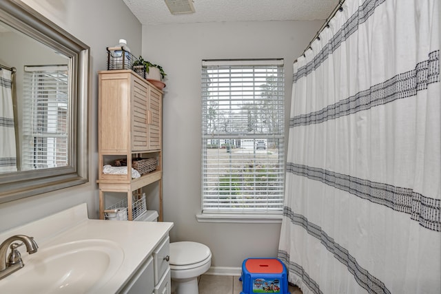 bathroom featuring vanity, a textured ceiling, tile patterned floors, and toilet