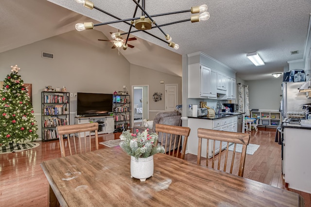 dining room with sink, vaulted ceiling, ceiling fan, a textured ceiling, and light hardwood / wood-style floors