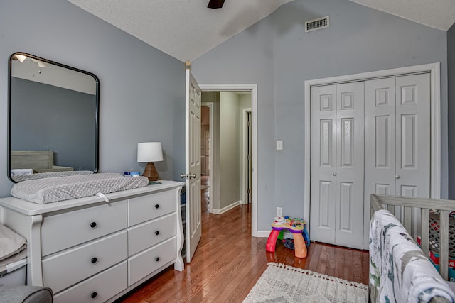 bedroom with a textured ceiling, light hardwood / wood-style floors, a closet, and lofted ceiling