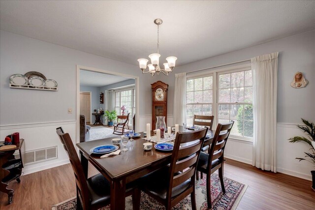 dining space with hardwood / wood-style flooring and an inviting chandelier