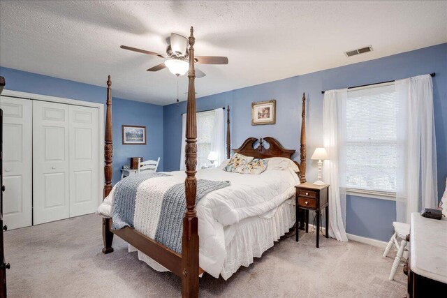 bedroom featuring light carpet, multiple windows, a closet, and ceiling fan