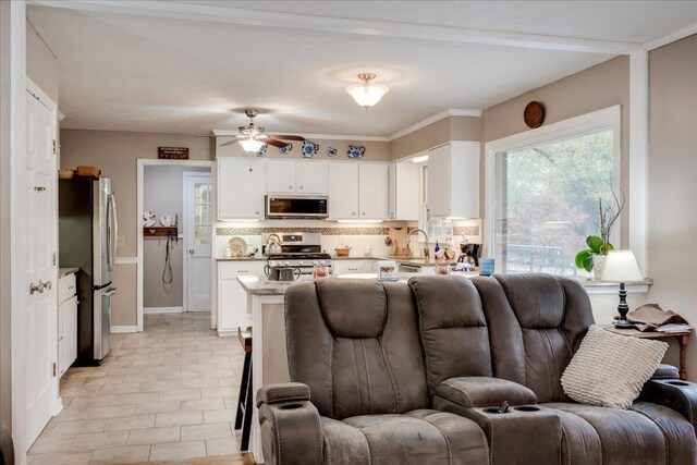 living room with ceiling fan and crown molding