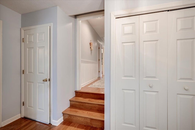 stairs featuring a textured ceiling and hardwood / wood-style flooring