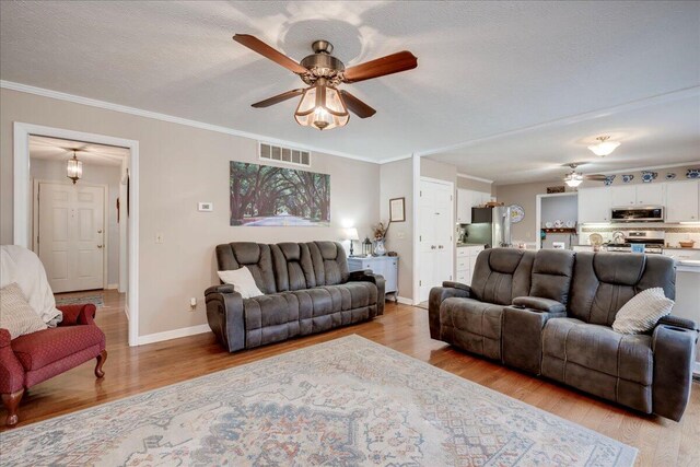 living room featuring light hardwood / wood-style floors, ceiling fan, and crown molding