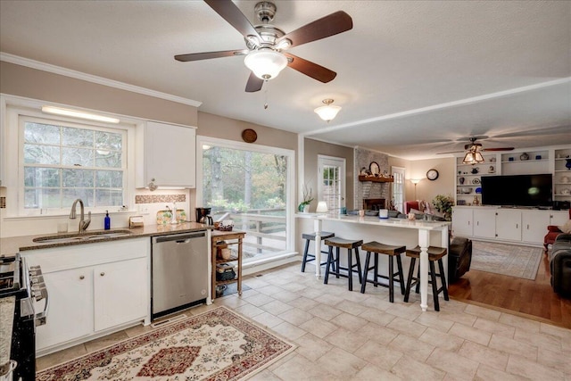 kitchen with white cabinetry, sink, ceiling fan, stainless steel appliances, and a kitchen breakfast bar