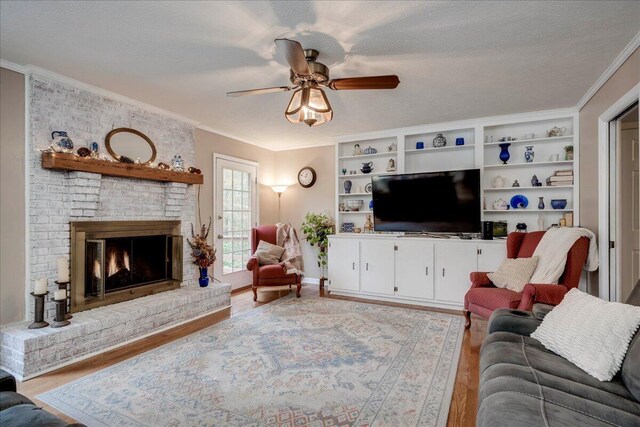 living room featuring ceiling fan, light wood-type flooring, a textured ceiling, and a brick fireplace