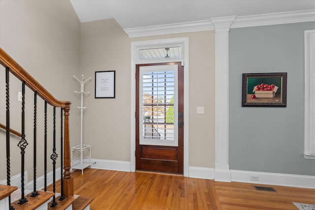 entryway featuring wood-type flooring, ornate columns, and crown molding