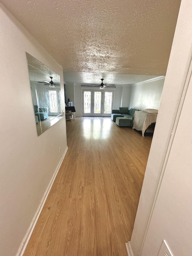 hall with french doors, a textured ceiling, and hardwood / wood-style flooring