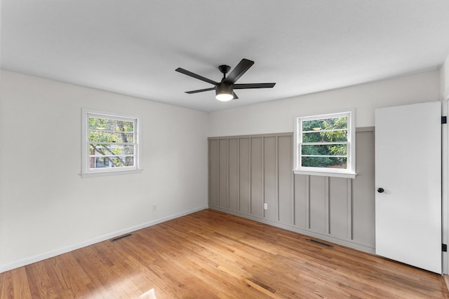 empty room with plenty of natural light, ceiling fan, and light hardwood / wood-style flooring