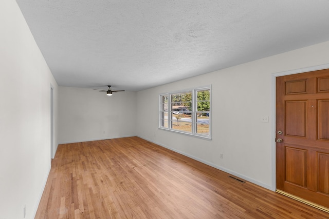 empty room with ceiling fan, light hardwood / wood-style flooring, and a textured ceiling