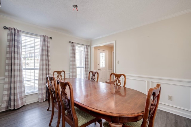 dining space featuring a wainscoted wall, crown molding, a textured ceiling, and dark wood-style flooring