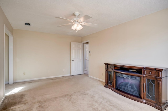 unfurnished living room with baseboards, a glass covered fireplace, visible vents, and light colored carpet